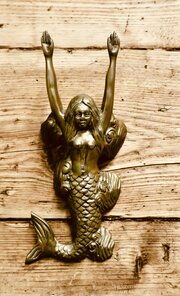 A Brass Door Knocker In The Shape Of A Mermaid